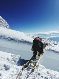 Rear view of man skiing on snowcapped mountain against clear sky