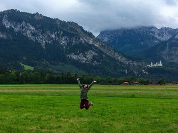 Woman jumping with arms outstretched at field
