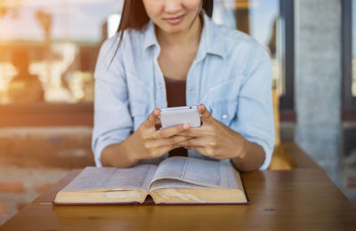 Young woman using mobile phone at table