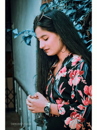 Young woman looking away while standing against wall