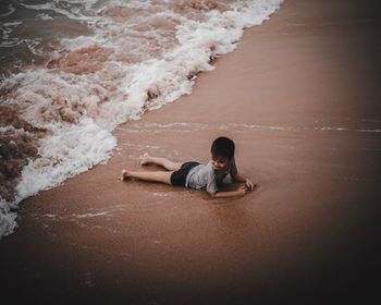Boy lying on shore at beach