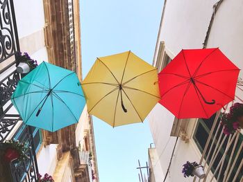 Low angle view of umbrellas hanging against buildings in city