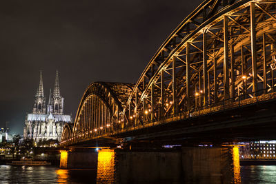 Illuminated suspension bridge over river at night