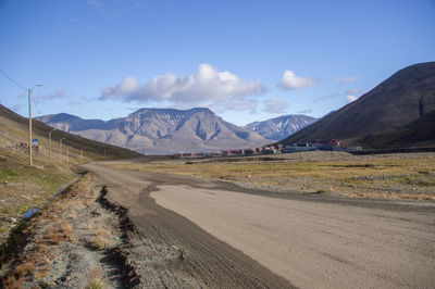 Road by mountains against sky