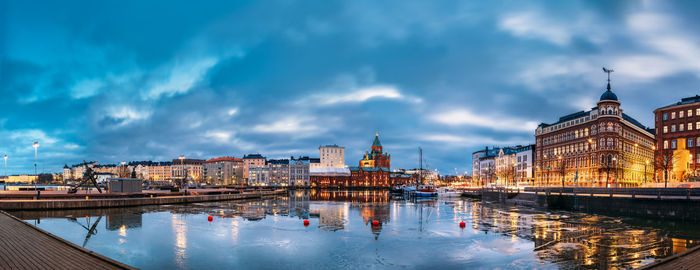 View of buildings and river against cloudy sky