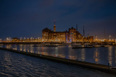 Illuminated buildings at waterfront sunset