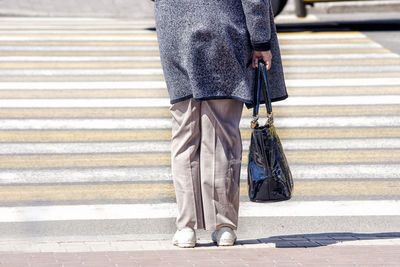 Low section of woman standing on sidewalk in city