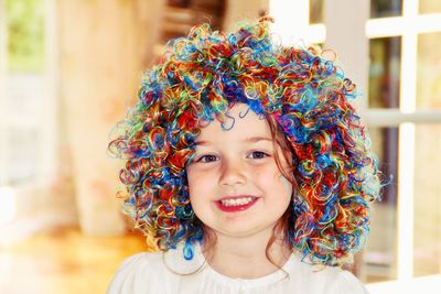 Close-up portrait of smiling child with colorful wig