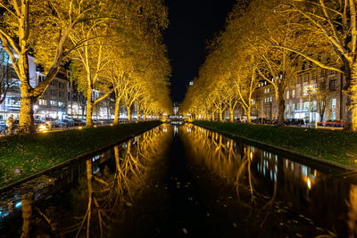 Illuminated bridge over lake in city at night