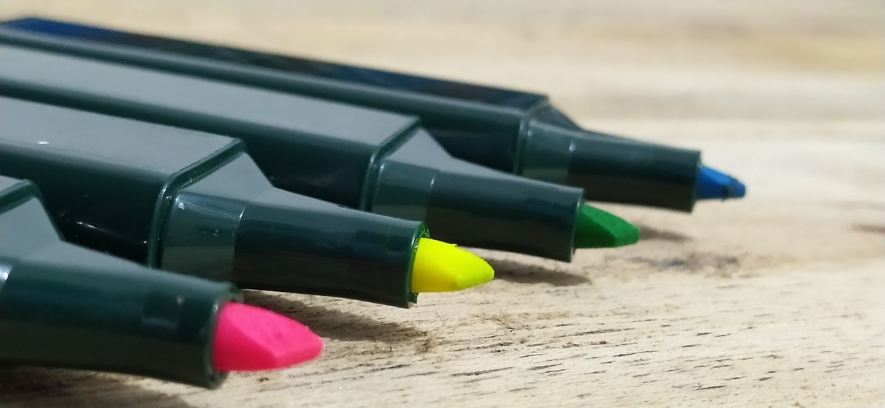 CLOSE-UP OF COLORED PENCILS ON SAND