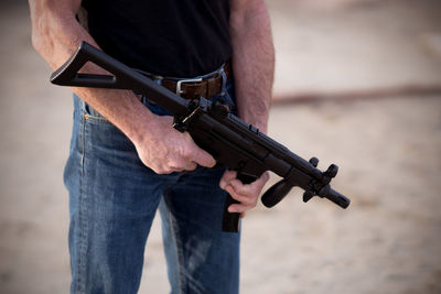 Midsection of man standing with gun