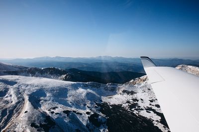 Aerial view of snowcapped mountains against clear blue sky