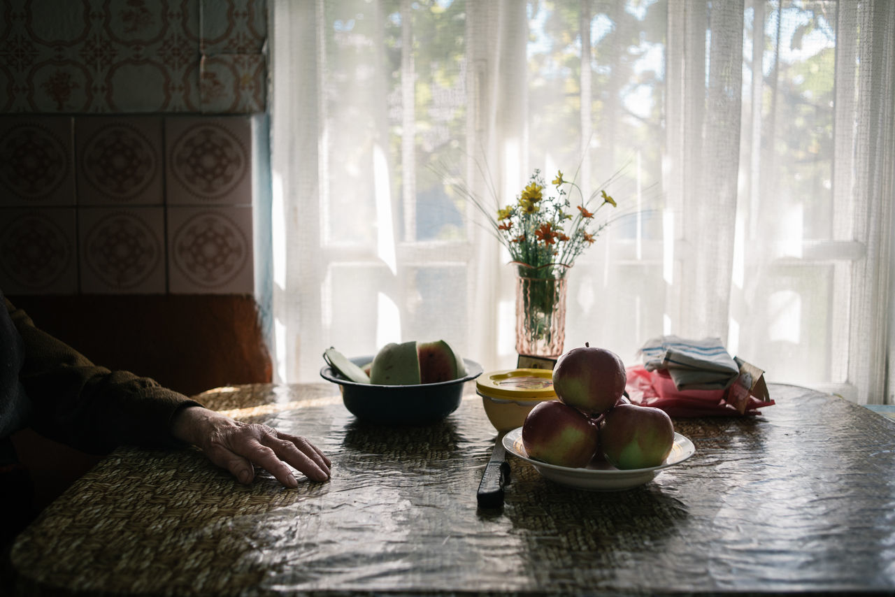indoors, vase, window, table, curtain, food and drink, bowl, home interior, day, real people, healthy eating, flower, food, freshness
