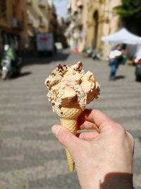 Close-up of hand holding ice cream cone on street