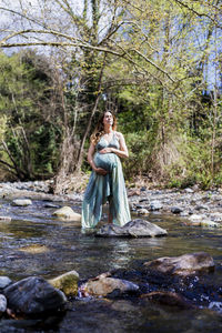 Woman standing by stream in forest