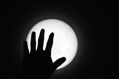 Close-up of silhouette hand against dark sky