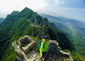 High angle view of man holding monopod while standing against mountains 
