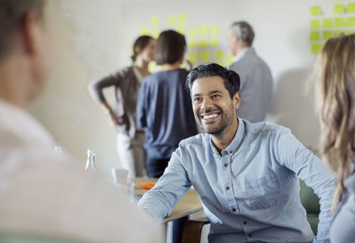 Happy businessman discussing with colleagues in board room