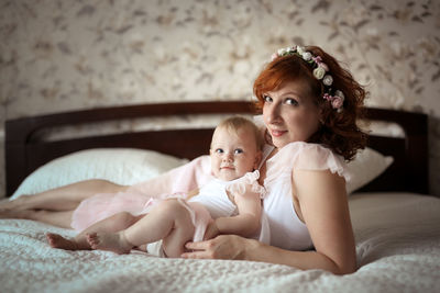 Gentle mother and daughter on the bed in a real room, the concept of motherhood and affection