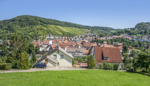 Houses by trees and buildings against clear sky