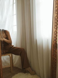 Reflection of woman sitting at home in mirror