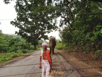 Woman walking on road amidst trees