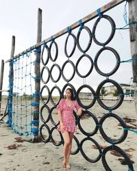 Rear view of woman standing on chainlink fence