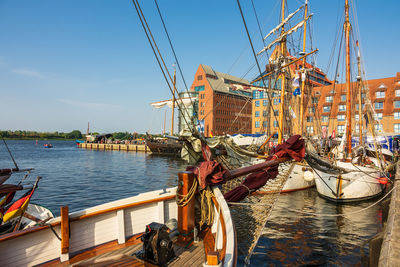 Sailboats moored on river in city against sky