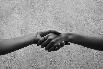 Midsection of woman holding hands against wall