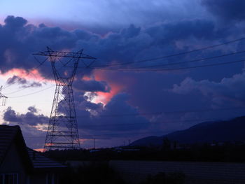 Electricity pylon against cloudy sky