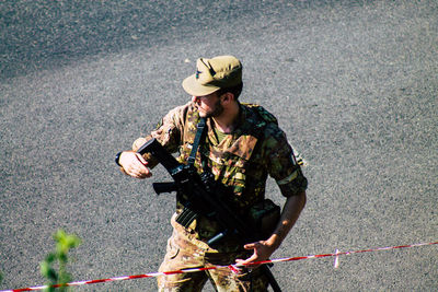 Full length of man wearing hat holding camera while standing outdoors