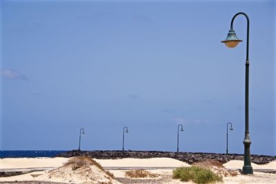 Street lights on beach against clear blue sky