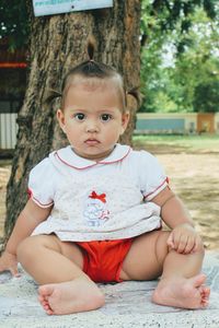 Portrait of cute baby girl sitting on tree