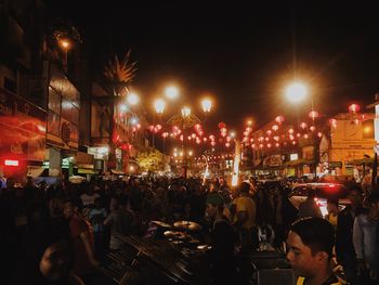 Crowd at illuminated city against sky at night