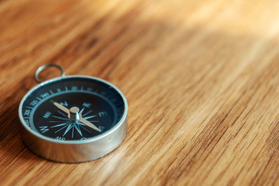 Close-up of navigational compass on wooden table