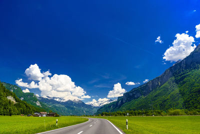 Road amidst field against sky