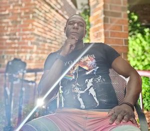 Full length of man sitting against wall