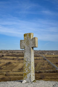 Cross on field against sky