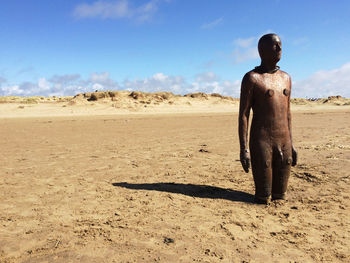 Rear view of shirtless man on sand