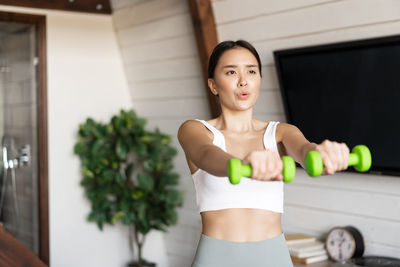Portrait of young woman exercising at home