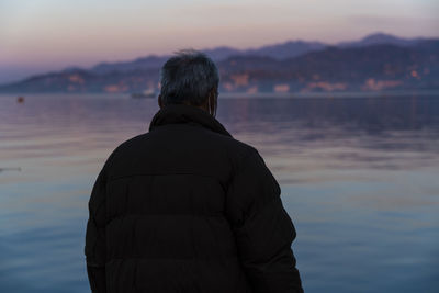 Rear view of man standing against sea during sunset