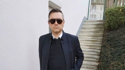 Young man wearing sunglasses standing against wall