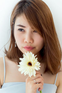 Close-up portrait of beautiful woman holding white flower