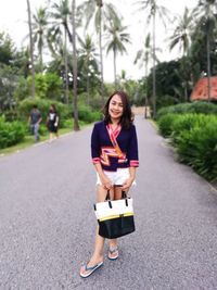 Portrait of young woman with umbrella standing on road