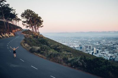 Road by cityscape against clear sky