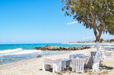 Empty seats at beach against sky