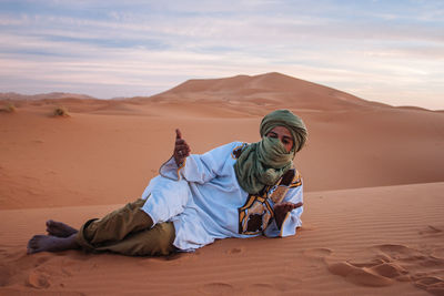 Man on sand dune in desert against sky