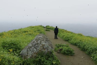 Rear view of man standing on mountain against sky