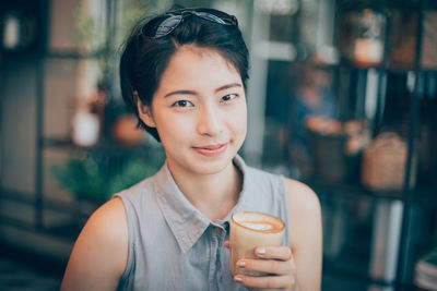 Close-up portrait of young woman drinking drink at cafe