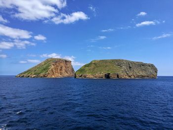 Built structure on rock by sea against blue sky